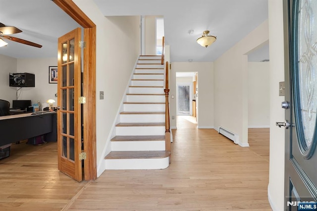 foyer entrance with ceiling fan, baseboards, baseboard heating, stairway, and light wood finished floors