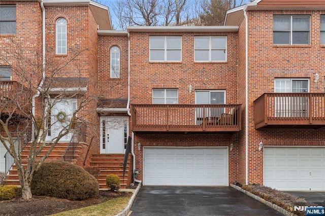 townhome / multi-family property featuring a garage, driveway, and brick siding