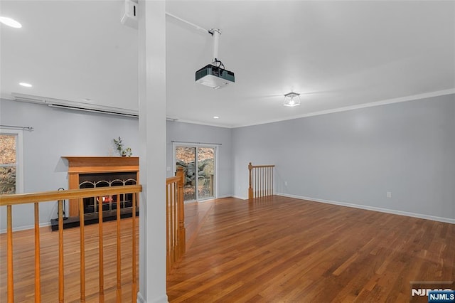 empty room featuring baseboards, a fireplace, ornamental molding, and wood finished floors