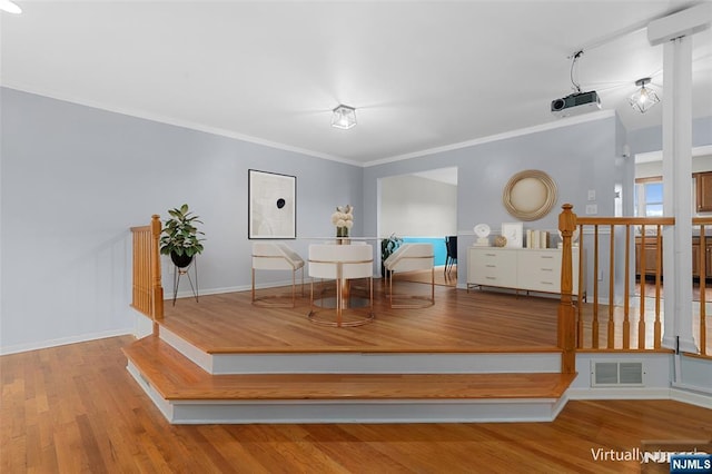 unfurnished dining area with baseboards, crown molding, visible vents, and wood finished floors