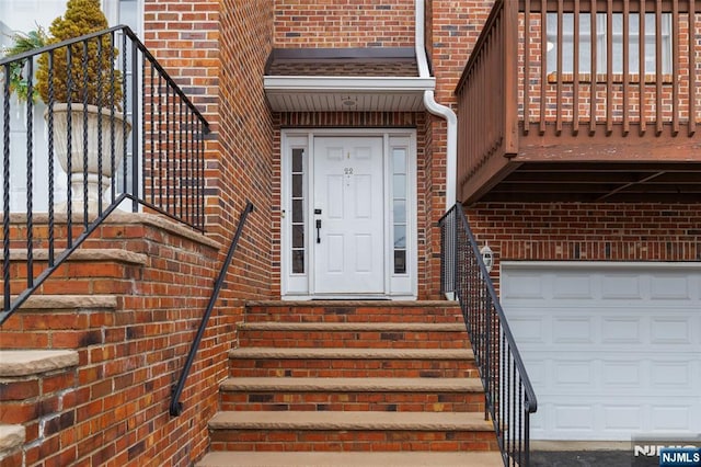 entrance to property with a garage and brick siding