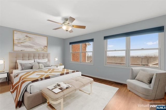 bedroom featuring visible vents, wood finished floors, a ceiling fan, and baseboards