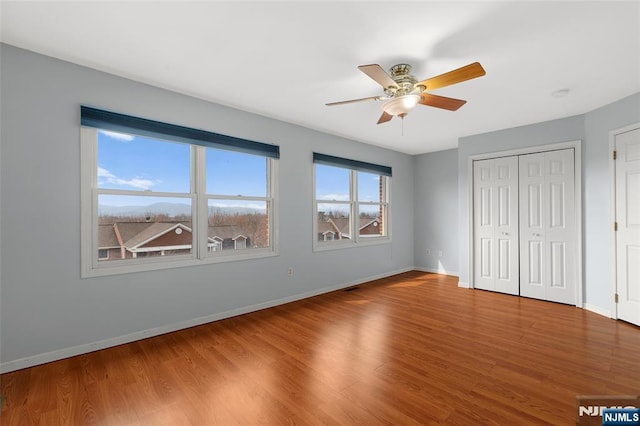 unfurnished bedroom featuring a ceiling fan, a closet, baseboards, and wood finished floors