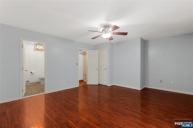 unfurnished bedroom with ceiling fan with notable chandelier, ensuite bath, wood finished floors, and baseboards