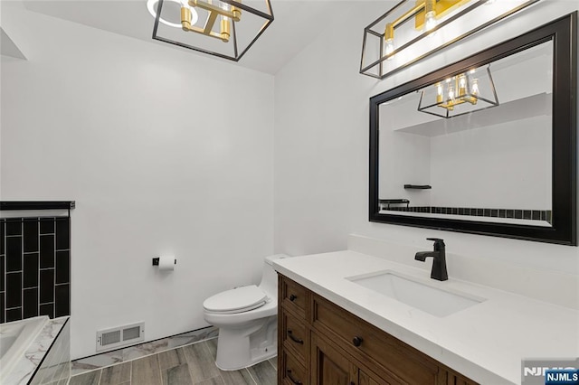 full bath with tiled bath, toilet, wood finished floors, vanity, and visible vents