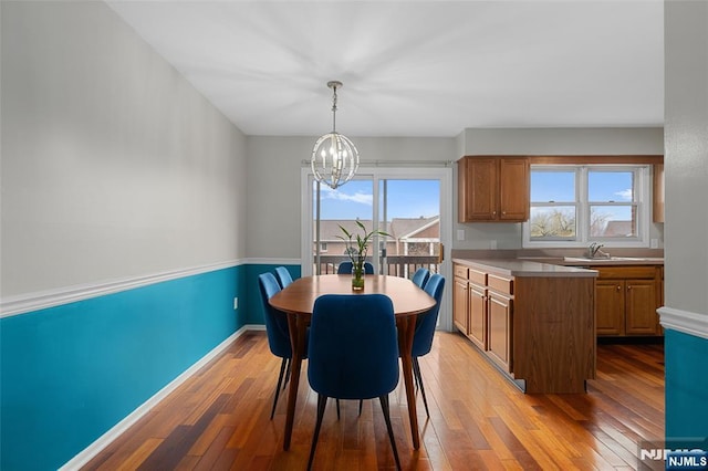 dining room featuring baseboards, light wood-type flooring, and an inviting chandelier