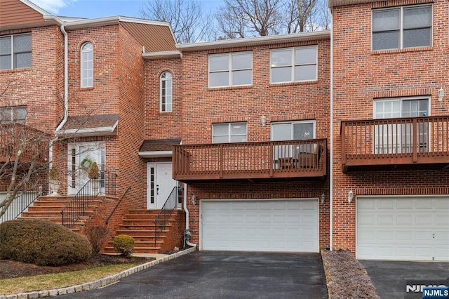 view of property with driveway, a garage, and brick siding