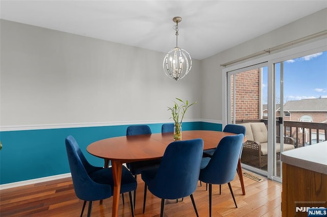 dining room with light wood-style floors, baseboards, and a chandelier