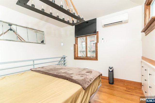 bedroom with an AC wall unit and wood finished floors