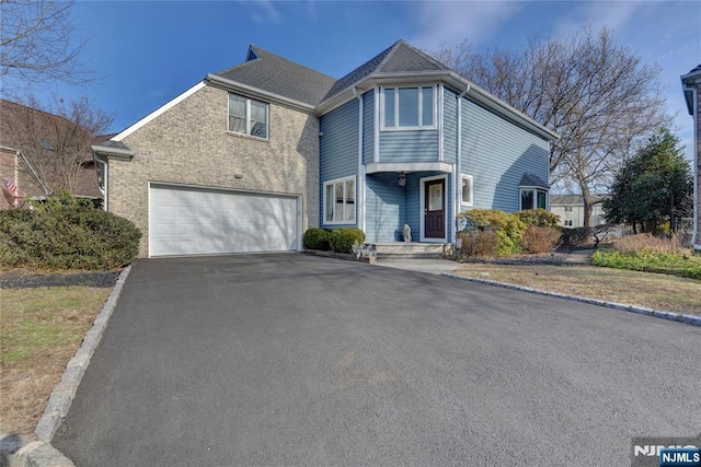 view of front of home featuring a garage, aphalt driveway, and brick siding