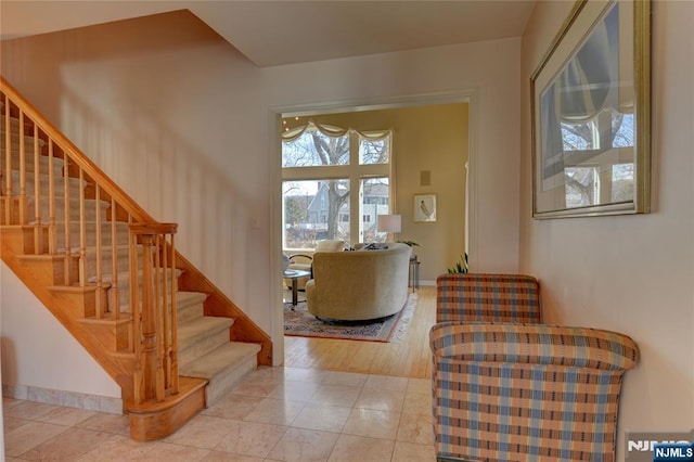 entryway featuring light tile patterned flooring, stairway, and baseboards