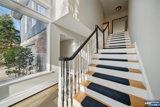 staircase featuring a high ceiling and wood finished floors