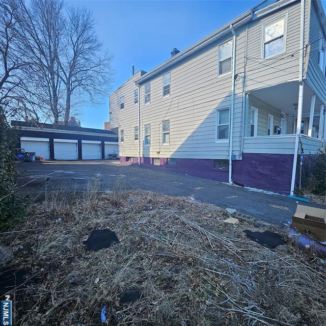 view of property exterior with an outdoor structure and community garages