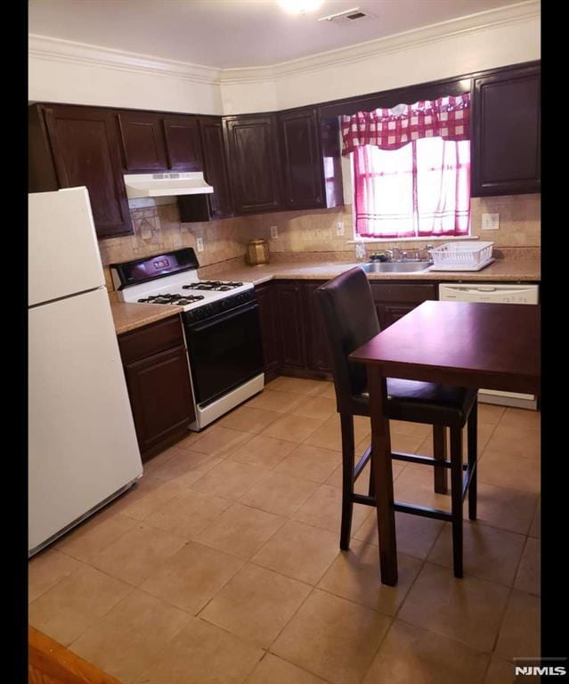 kitchen with dishwashing machine, under cabinet range hood, a sink, freestanding refrigerator, and gas range