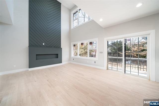 unfurnished living room with light wood-type flooring, a large fireplace, and baseboards