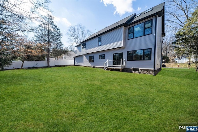 rear view of property featuring fence and a lawn