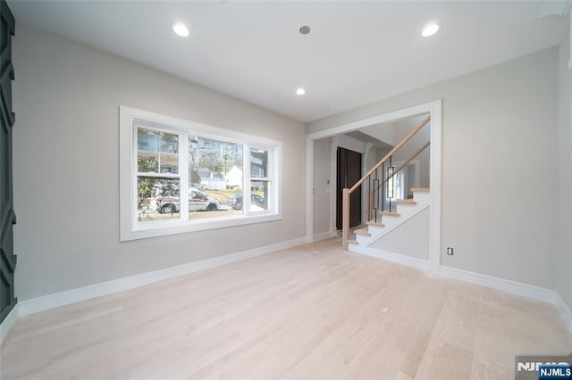 unfurnished living room featuring baseboards, stairway, and recessed lighting