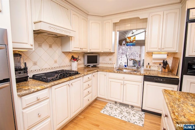 kitchen featuring a sink, custom range hood, dishwasher, black gas stovetop, and light wood-type flooring