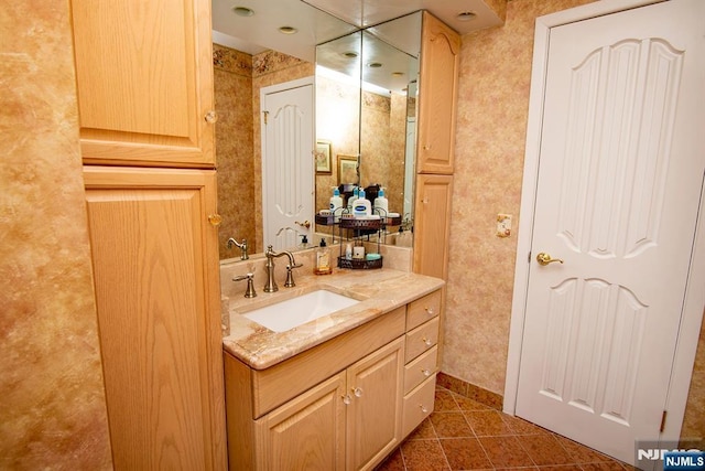 bathroom with vanity, tile patterned floors, baseboards, and wallpapered walls