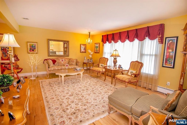 living area featuring light wood finished floors, visible vents, baseboards, baseboard heating, and an inviting chandelier