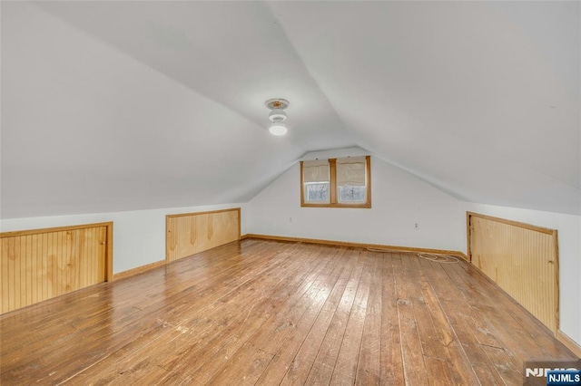 bonus room with vaulted ceiling, light wood finished floors, and baseboards