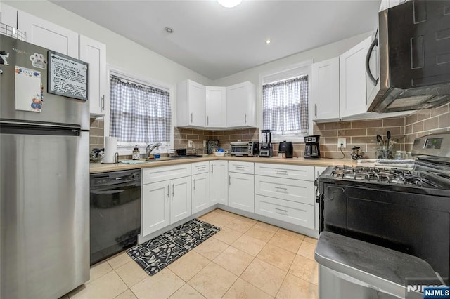 kitchen with light tile patterned floors, stainless steel appliances, white cabinets, light countertops, and decorative backsplash