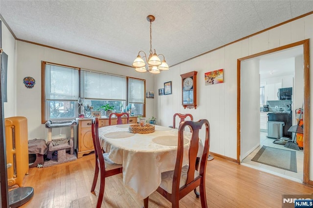 dining area with a notable chandelier, radiator, ornamental molding, light wood-type flooring, and baseboards