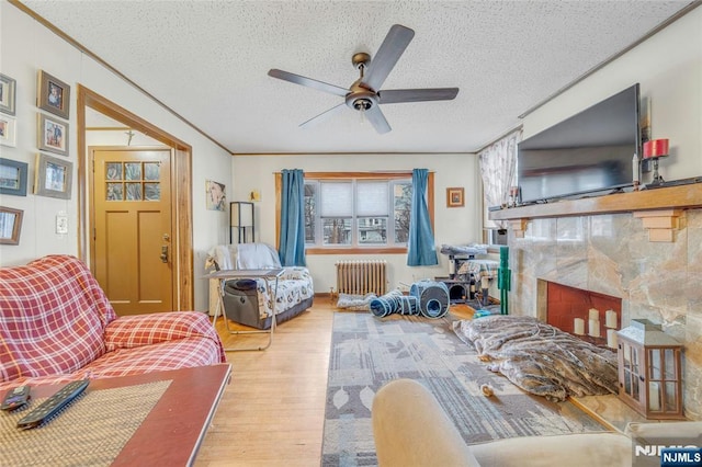 living room featuring a fireplace, a textured ceiling, radiator heating unit, and wood finished floors