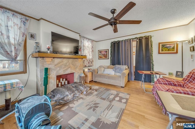 living area featuring a textured ceiling, ornamental molding, a fireplace, and wood finished floors