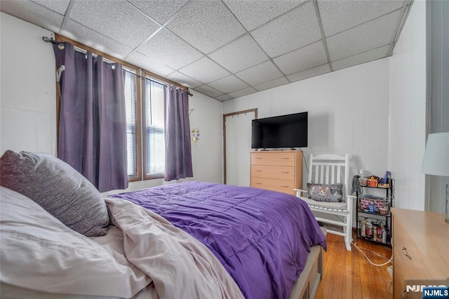 bedroom with a paneled ceiling and wood finished floors