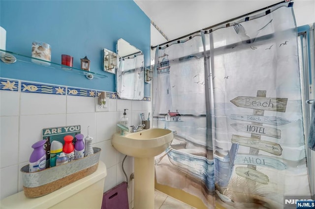 bathroom featuring toilet and tile walls