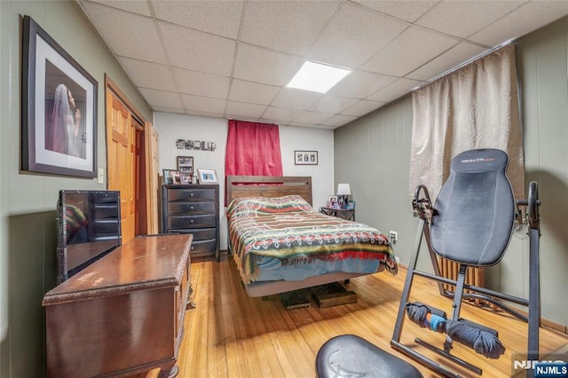 bedroom featuring a drop ceiling and wood finished floors