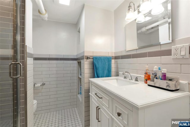 bathroom featuring a wainscoted wall, a tile shower, tile walls, and vanity