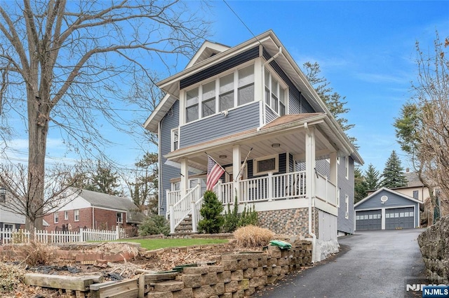 view of front of property featuring covered porch, a detached garage, fence, and an outdoor structure