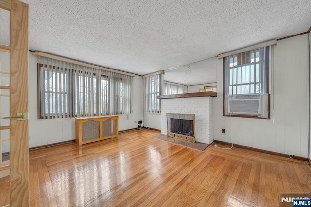 unfurnished living room featuring a textured ceiling, wood-type flooring, a fireplace, and cooling unit