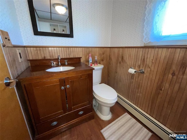 bathroom featuring a baseboard heating unit, wainscoting, toilet, and wallpapered walls