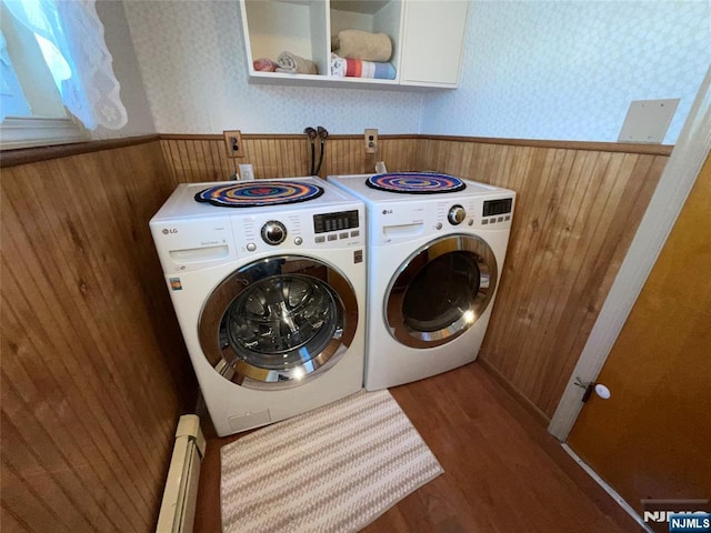 washroom with wooden walls, a wainscoted wall, a baseboard heating unit, wood finished floors, and washer and dryer