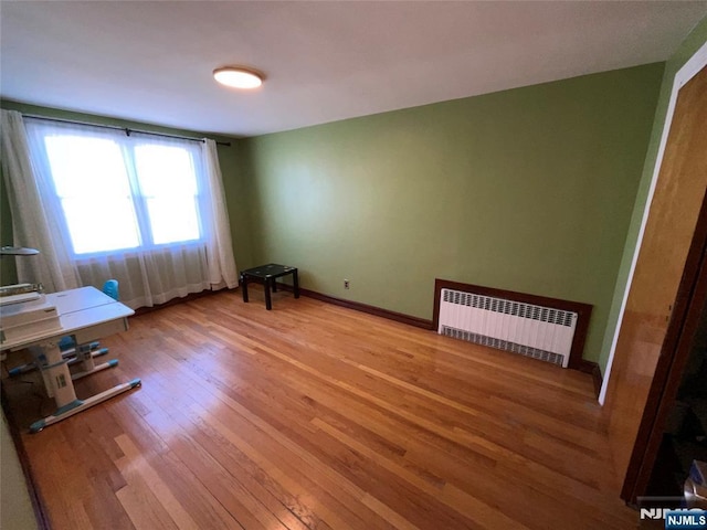 interior space with radiator heating unit, light wood-type flooring, and baseboards