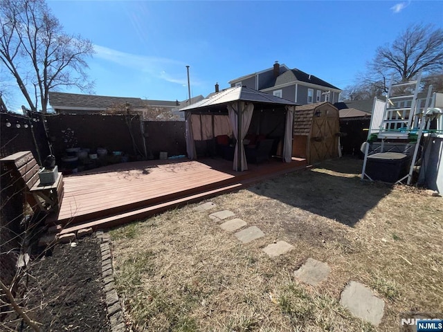 back of property featuring an outbuilding, a gazebo, a storage shed, fence, and a wooden deck