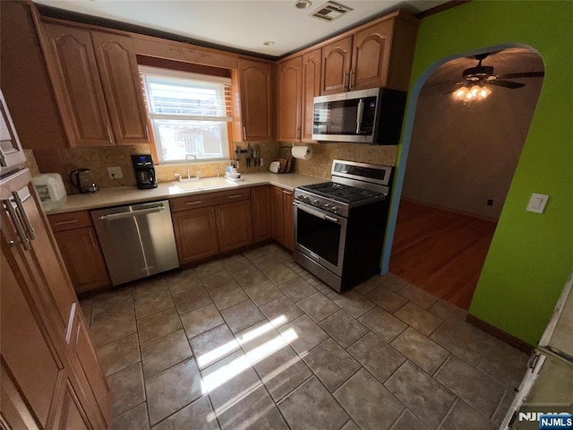 kitchen with arched walkways, stainless steel appliances, a sink, and light countertops