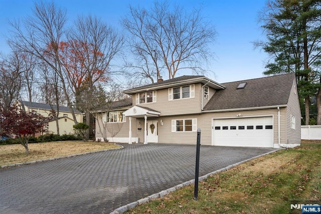 view of front facade featuring roof with shingles, aphalt driveway, a chimney, and an attached garage