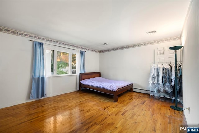 bedroom featuring a baseboard radiator, visible vents, and hardwood / wood-style floors