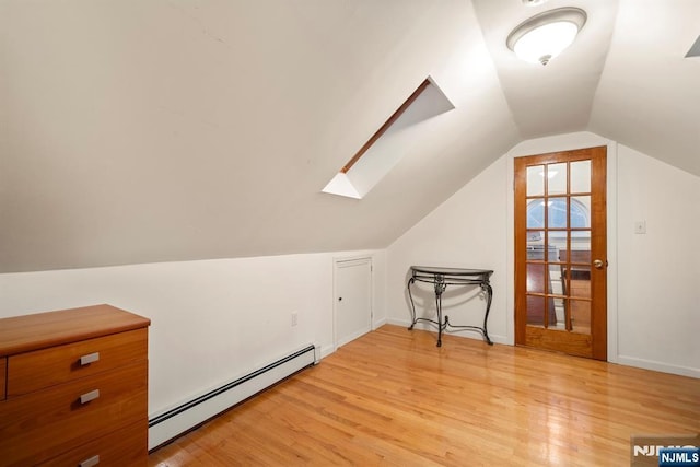 bonus room with a baseboard heating unit, lofted ceiling with skylight, baseboards, and light wood-style floors