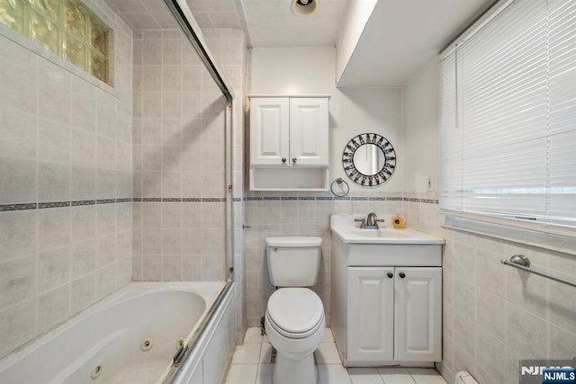 full bath with tile walls, toilet, wainscoting, vanity, and tile patterned flooring