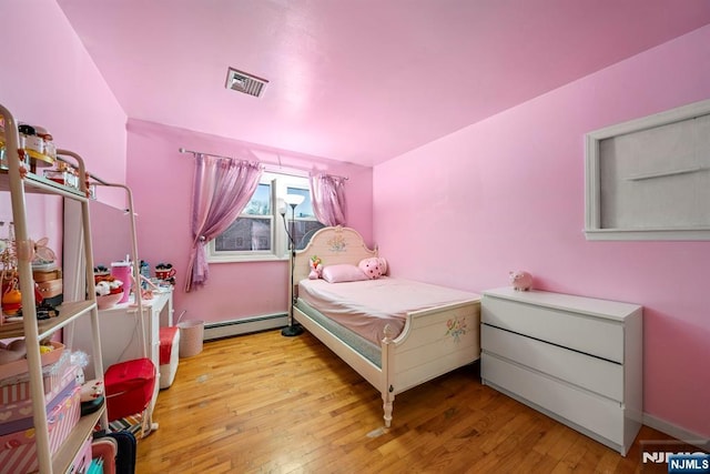 bedroom featuring a baseboard radiator, visible vents, and wood finished floors