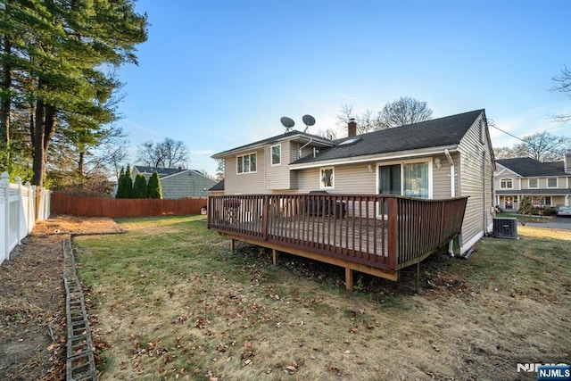 rear view of house featuring a fenced backyard, a chimney, a deck, a yard, and central air condition unit