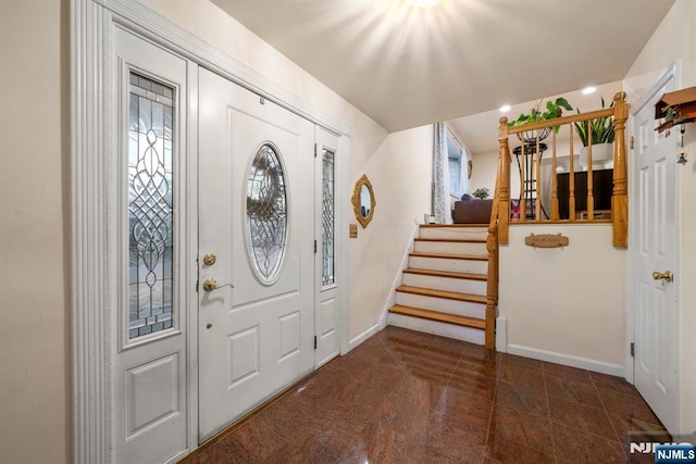 foyer entrance featuring stairs and baseboards