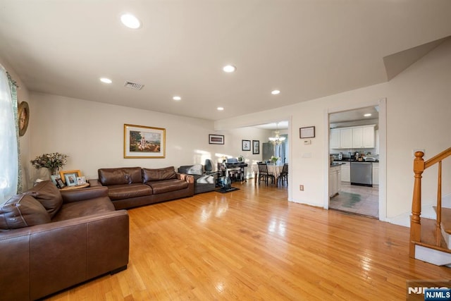 living room with stairs, light wood-style flooring, visible vents, and recessed lighting