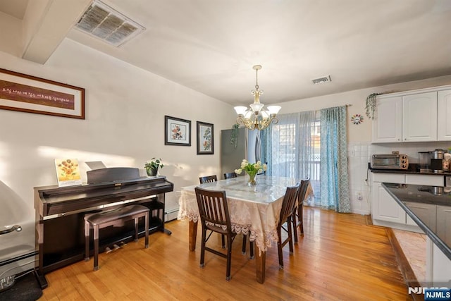 dining room with light wood-type flooring, visible vents, and a notable chandelier