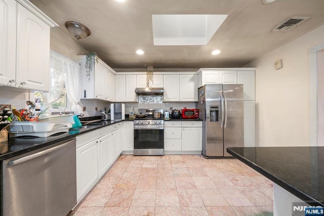 kitchen with stainless steel appliances, white cabinetry, visible vents, and decorative backsplash